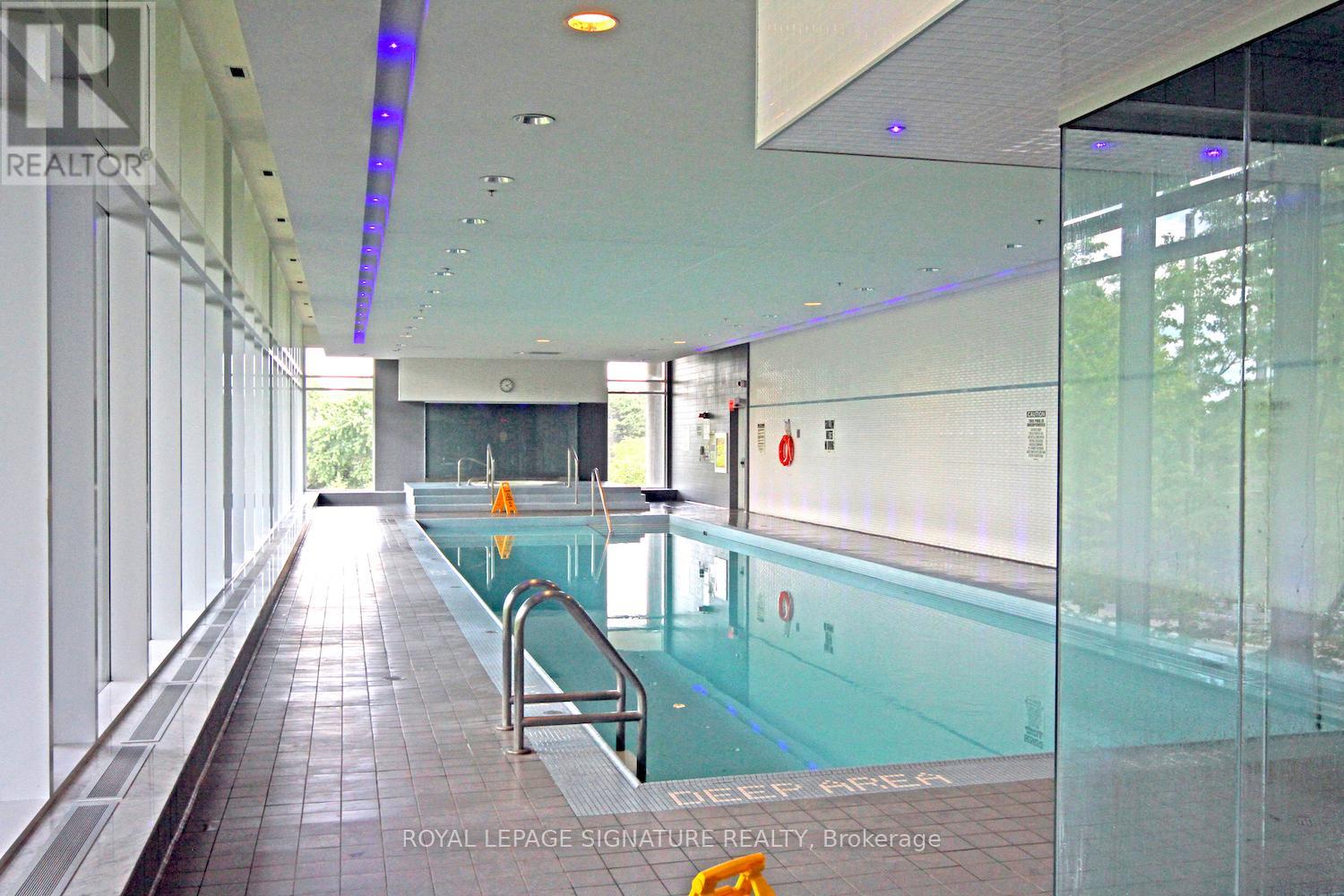 A swimming pool inside a building with a glass wall on one side.