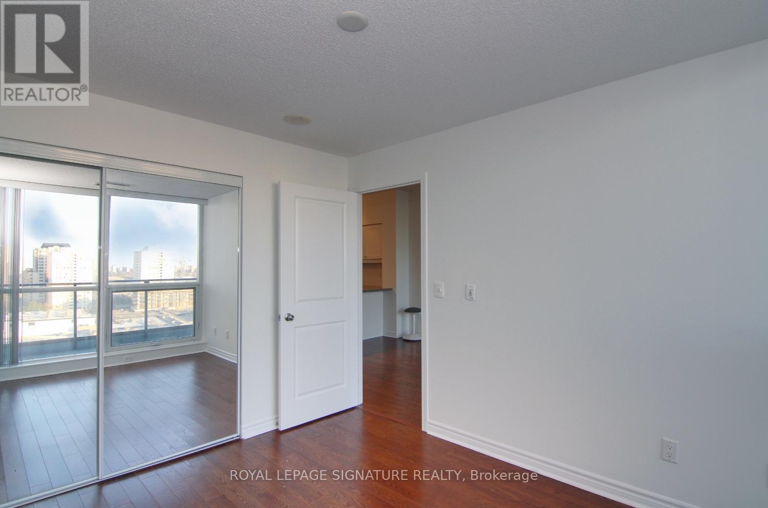 A white room with a sliding glass door and a wooden floor.