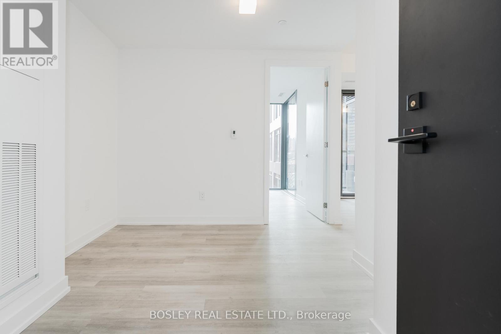 A room with a wooden floor and white walls, with a door on the right side.