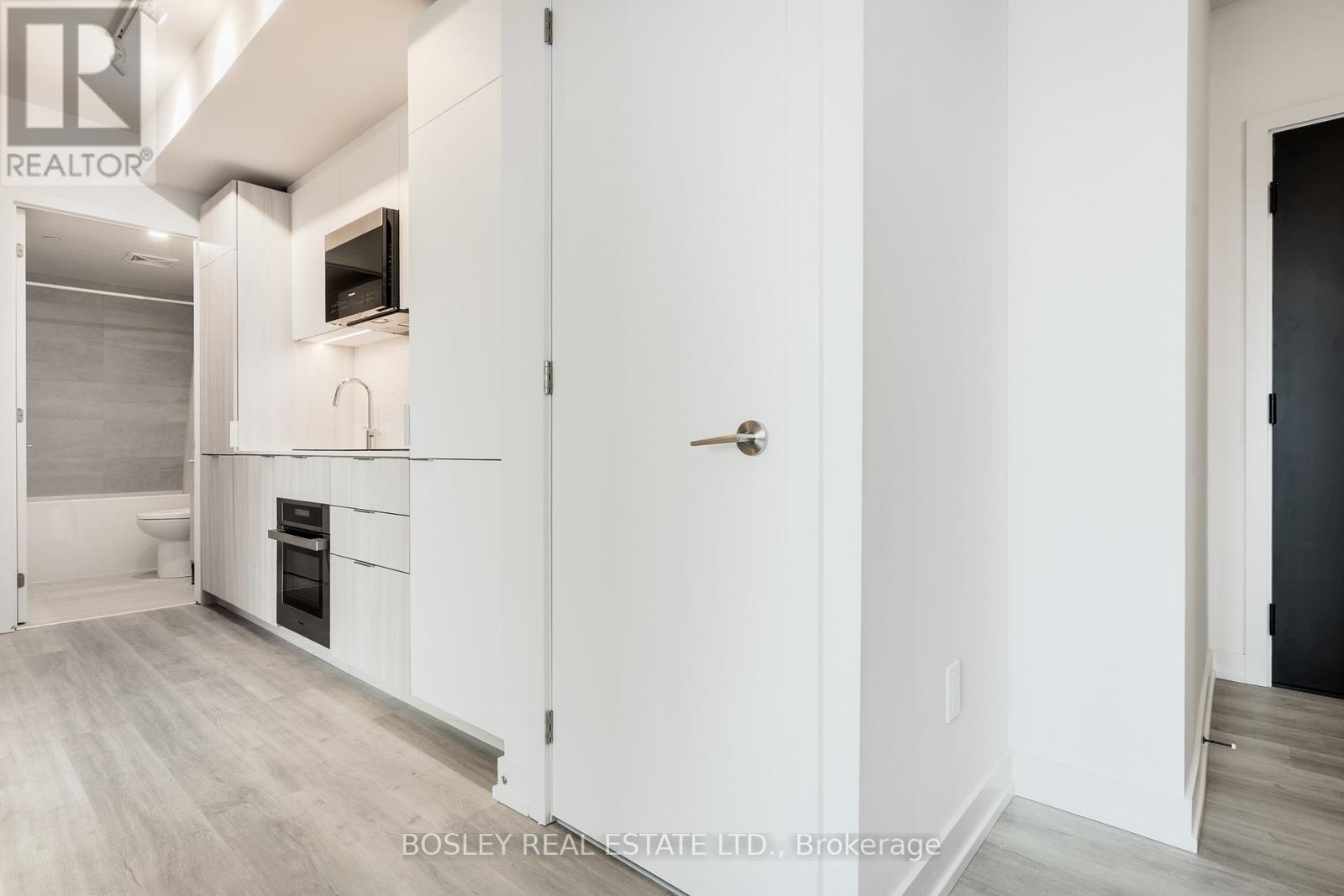 A modern kitchen with white cabinets and a wooden floor.