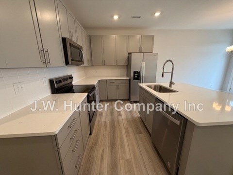A kitchen with white cabinets and a wooden floor.