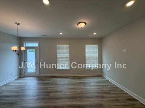 A spacious room with wooden flooring and a chandelier.