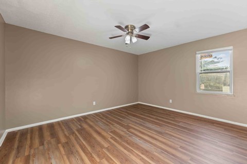 A room with wooden flooring and a ceiling fan.