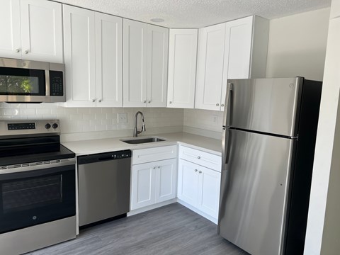 A modern kitchen with white cabinets and stainless steel appliances.