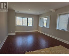 A room with wood flooring and two windows.