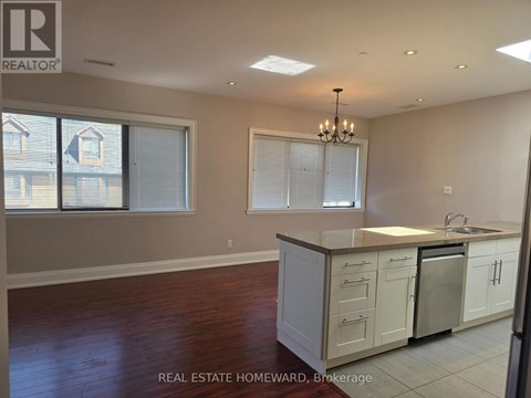 A kitchen with white cabinets and a wooden floor.