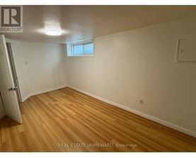 A room with wooden flooring and white walls, with a window and a door visible.