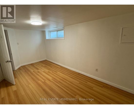 A room with wooden flooring and white walls, with a window and a door visible.