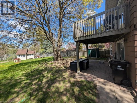 A wooden deck with a black trash can on a patio.