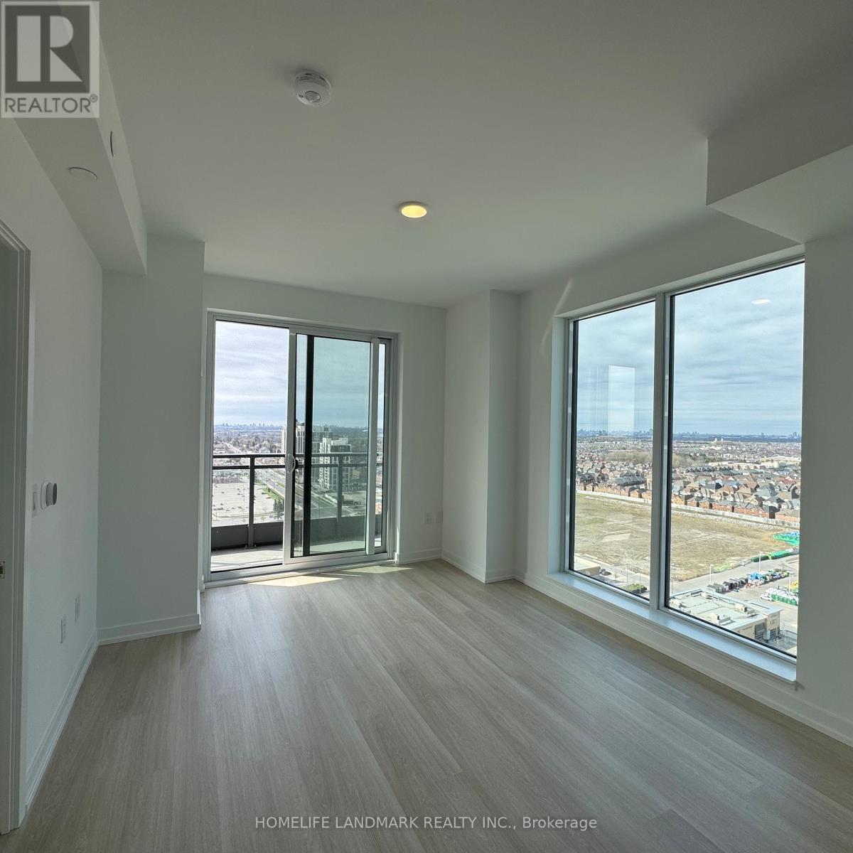 A spacious room with a view of the cityscape through large windows.