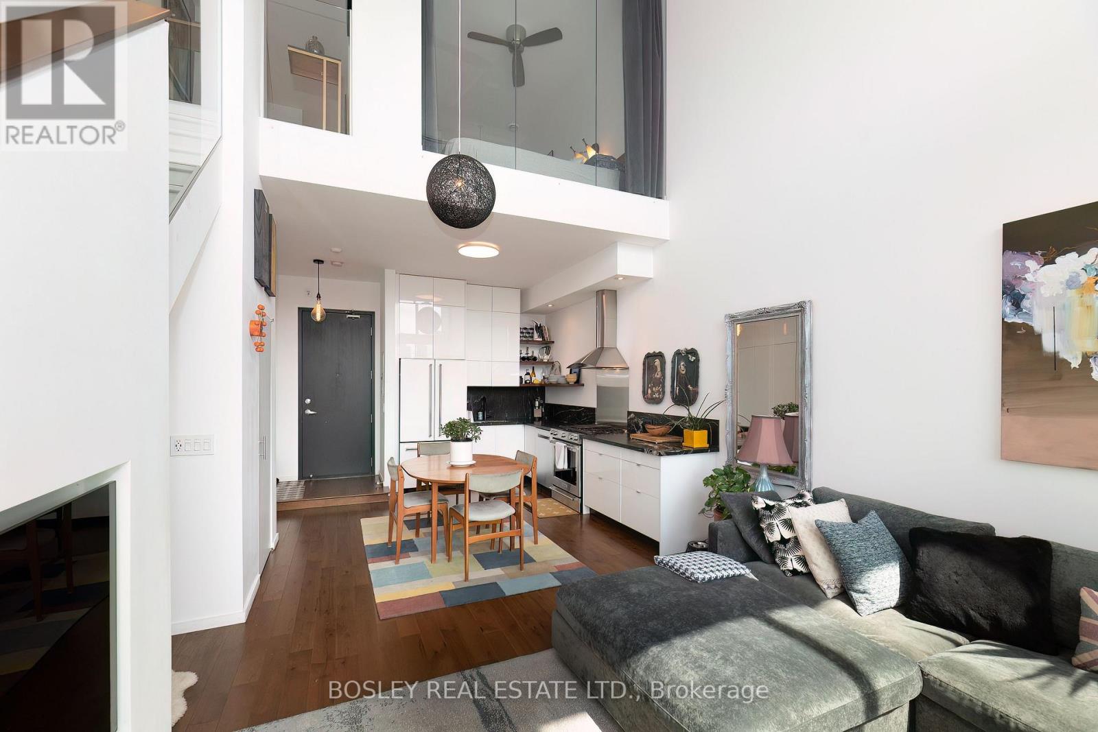 A modern living room with a grey couch and a wooden dining table.