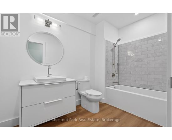 A white bathroom with a round mirror and a white toilet.