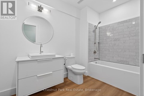 A white bathroom with a round mirror and a white toilet.