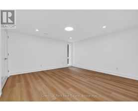 A room with wood flooring and white walls, with a door on the right side.