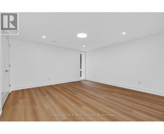 A room with wood flooring and white walls, with a door on the right side.