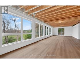 A room with wooden floors and a large window overlooking a wooded area.
