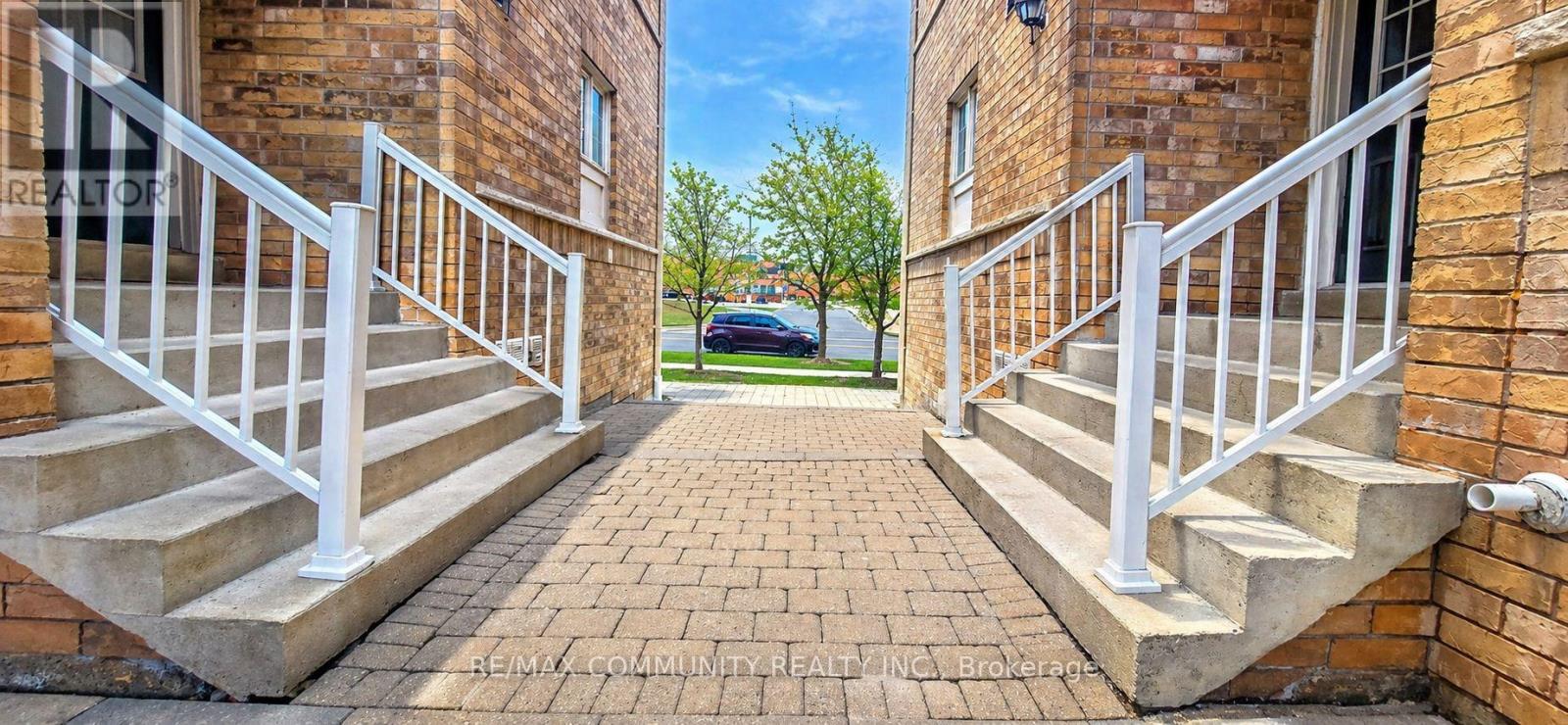 A brick building with a white railing on the stairs.