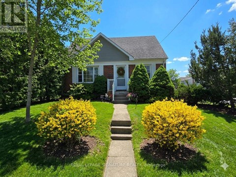 A house with a lawn and a bush with yellow flowers in front.