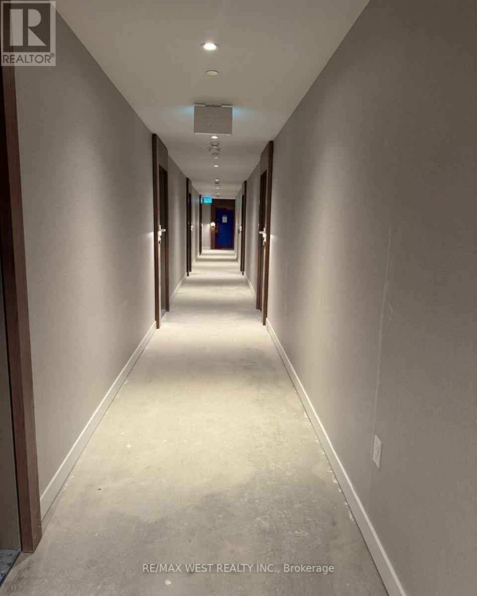A long, narrow hallway with a light on the ceiling and doors at the end.
