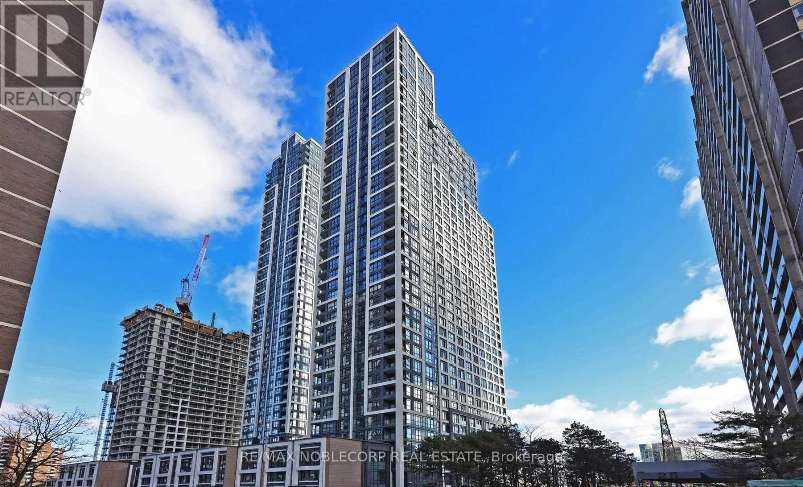 A tall building with many windows is under construction with a crane visible in the background.