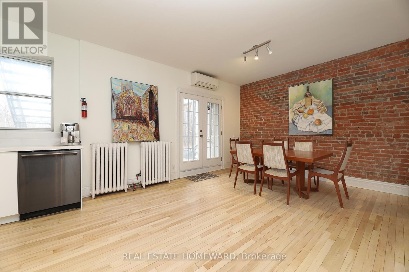 A room with a wooden floor and a brick wall with a painting on it.