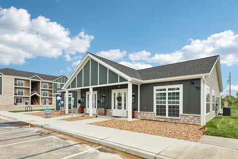 A building with a grey roof and white doors is surrounded by a parking lot.