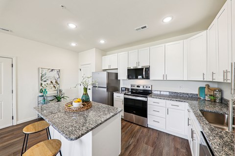 A kitchen with white cabinets and a granite countertop.