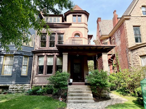 A large house with a front porch and a staircase leading to the entrance.