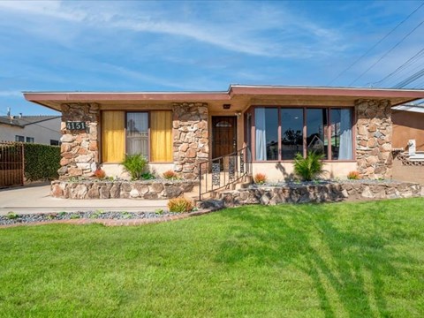 A house with a stone wall and a yellow door.