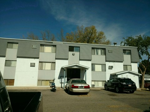 A grey building with a car parked in front.