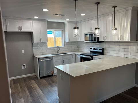 A kitchen with a white counter top and stainless steel appliances.
