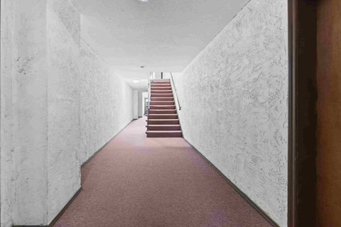 A long hallway with a staircase in the distance.