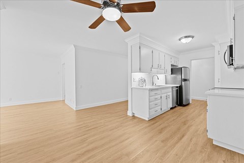 A kitchen with white cabinets and a ceiling fan.