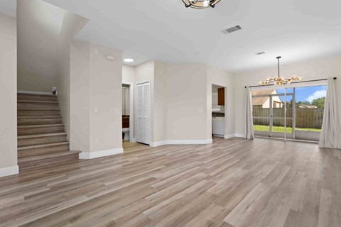 A spacious room with wooden flooring and a chandelier.