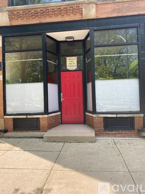 A red door is the only entrance to a building with a glass window.
