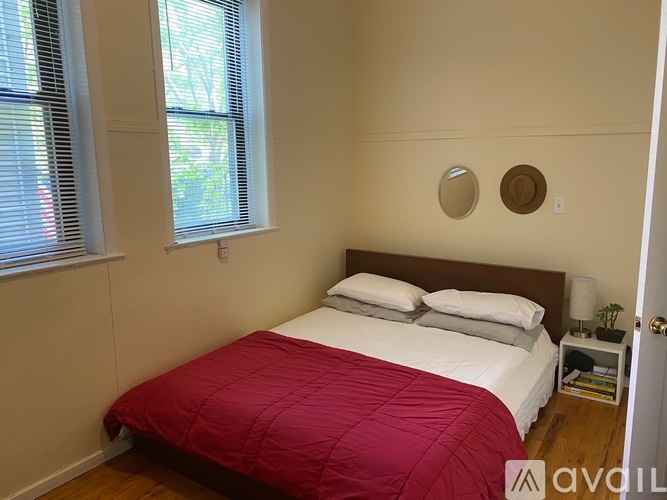 A bedroom with a bed covered in a red comforter.