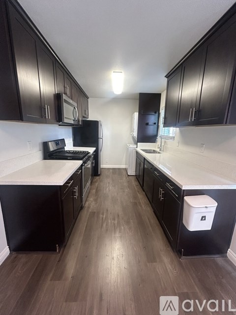 A kitchen with dark wood cabinets and a white counter.