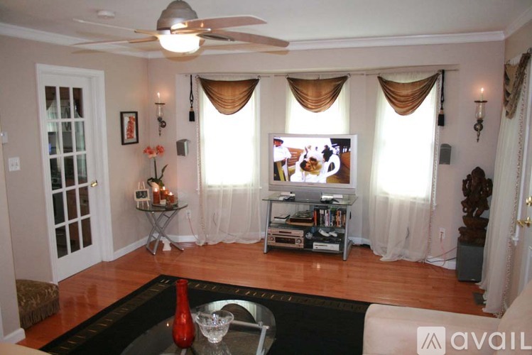 A living room with a television, a glass table, and a fan.