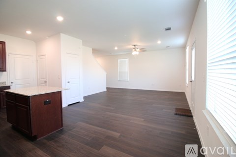 A spacious room with wooden flooring and white walls.