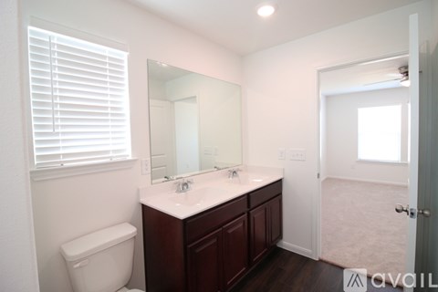 A bathroom with a toilet, sink, and mirror.