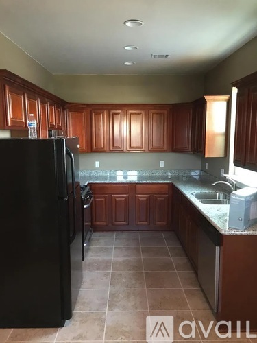 A kitchen with brown cabinets and a black refrigerator.