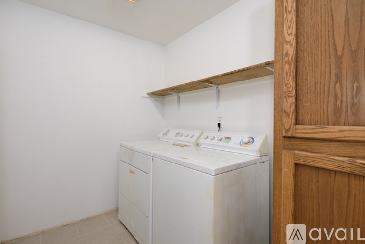 A white washing machine sits in a small laundry room.
