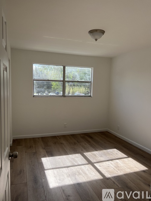 A room with a window and wooden flooring.