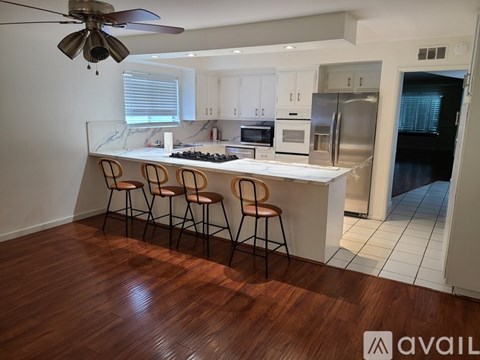 A kitchen with a bar stool and a ceiling fan.