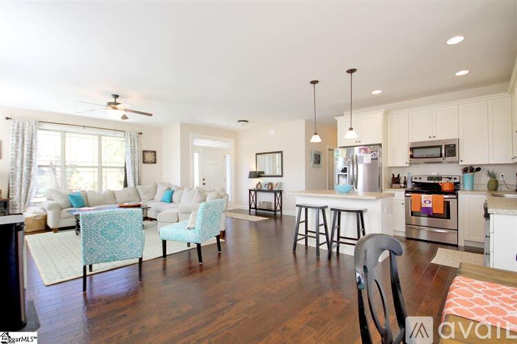 A modern kitchen with white cabinets and a wooden floor.