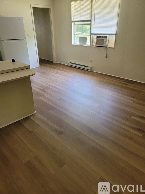 A kitchen with a white fridge and wooden floors.