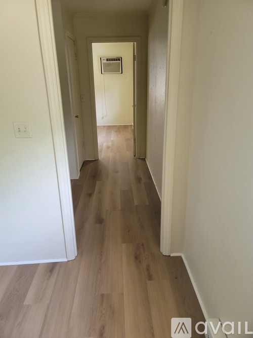 A long hallway with wood floors and white walls.