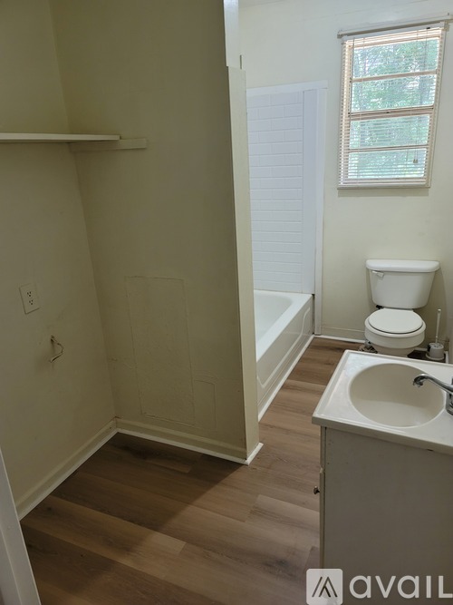 A bathroom with a toilet, sink, and a window.