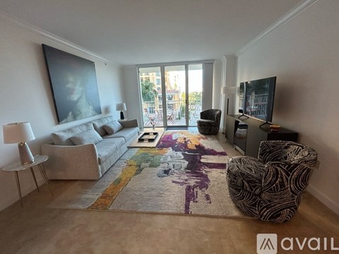A living room with a grey couch, a patterned rug, a chair, a small table, a television, and a painting on the wall.