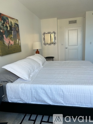 A bedroom with a large bed and a painting on the wall.